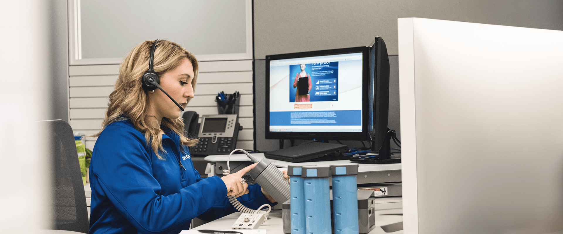 Woman at her desk speaks into headset while holding Novocure device.